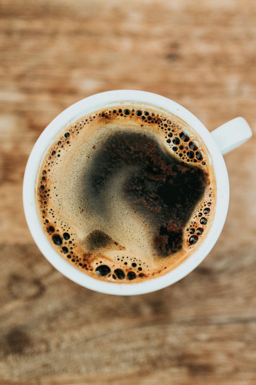 Cup of black drip coffee on a wooden table
